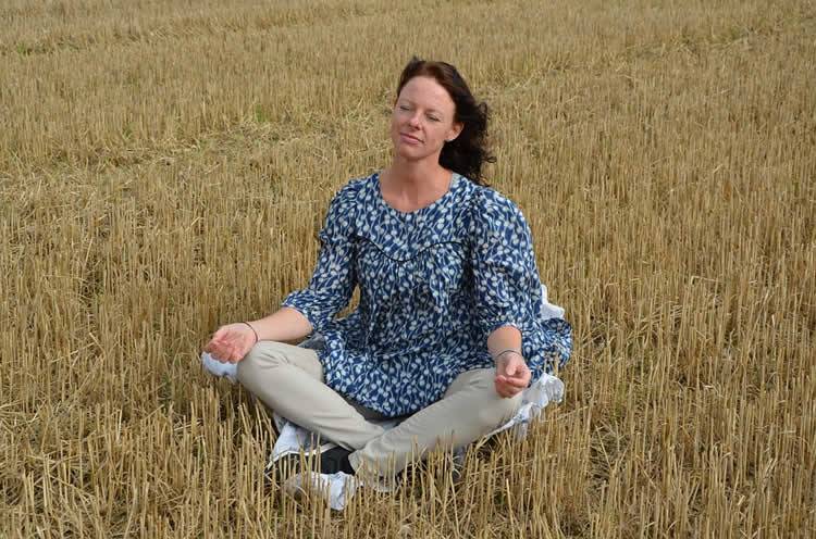 Image shows a woman meditating.