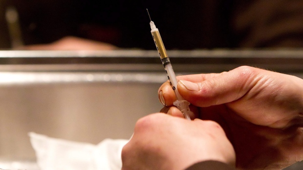 A person prepares a needle at a supervised injection site in Toronto.