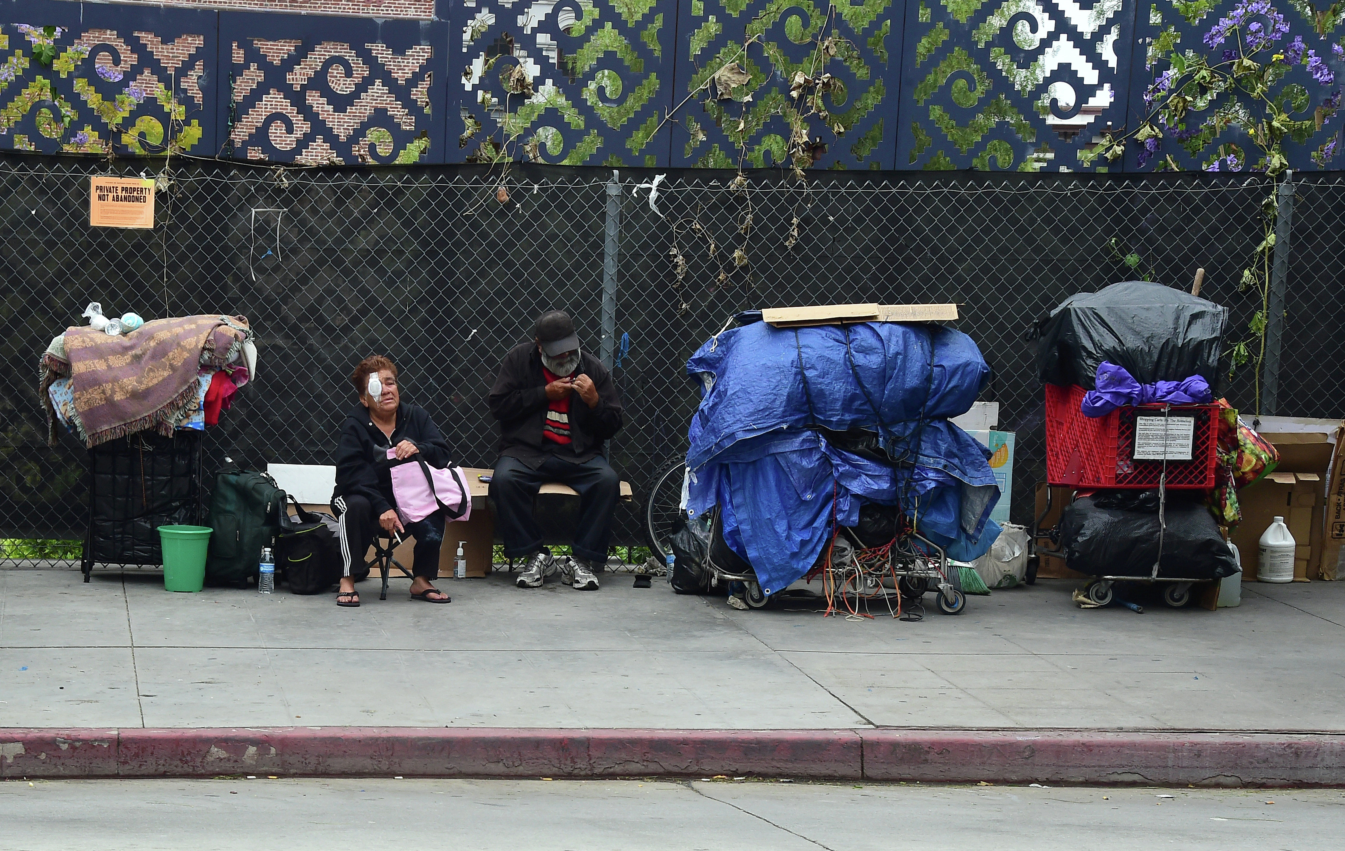 Homeless residents sit beside their belongings in downtown Los Angeles