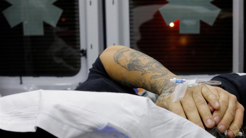 A man found unconscious after overdosing on opioids puts his hands over his head in the back of an ambulance in the Boston suburb of Malden, Massachusetts, December 2, 2017 [Brian Snyder/Reuters]